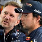 Un director de equipo y un piloto conversan en los boxes durante una carrera de Fórmula 1.