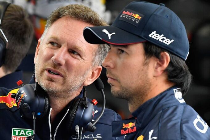 Un director de equipo y un piloto conversan en los boxes durante una carrera de Fórmula 1.