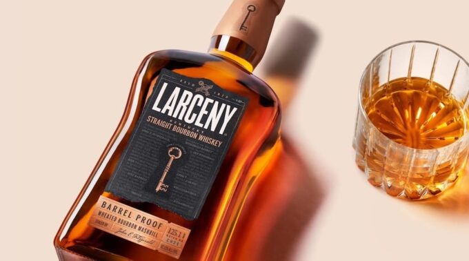 Botella de LARCENY Bourbon Whiskey con un vaso lleno de whisky al lado.